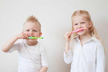 可爱的金发小女孩和有牙刷的男孩。 有趣的家庭游戏。 孩子们微笑。 健康的生活方式不怕牙医办公室。 牙科卫生