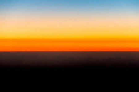 地平线上的橙色天空和云彩，美丽的金色橙色日落时间或光日出自然，图片从飞机。