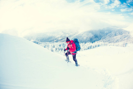 一个穿着雪鞋和在山上徒步旅行的人。 冬季旅行。 攀登攀登者在美丽的天空与云。 积极的生活方式。 在雪地里爬山。