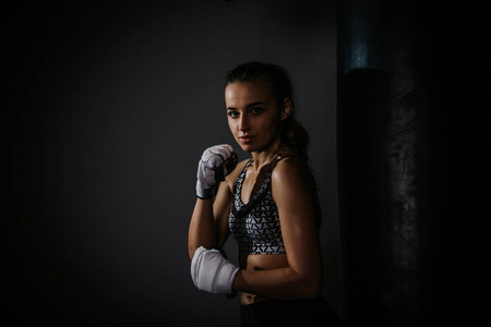 年轻漂亮的拳击手在黑暗的健身房里