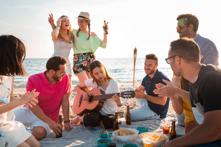 多文化的朋友在海滩上聚会，快乐的年轻人在暑假庆祝。暑假时间和假期概念。