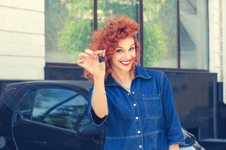 肖像快乐，微笑，年轻，有吸引力的女人买家靠近她的新车，显示给钥匙孤立的外部经销商经销商经销商停车场办公室。 个人交通汽车购买概念