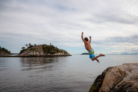 冒险的人是悬崖，从岩石跳到海洋。 在加拿大温哥华西部的Whytecliff公园马蹄湾。