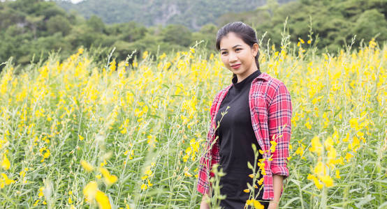 年轻漂亮的女人站在花田里享受。