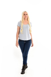 全长肖像金发女孩穿蓝色衬衫和牛仔裤站姿孤立在白色工作室背景。