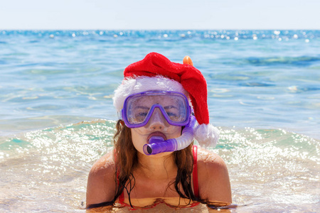 海滩度假有趣的女人戴着面具筒和圣诞帽在海水中游泳。 特写一个女孩在旅行假期的肖像。
