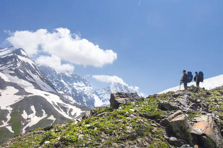 高山风景与两位徒步旅行者在高山山顶看雪山在晴朗的夏日。登山者徒步攀登。格鲁吉亚上斯瓦涅季亚地区的休闲活动。远足运动