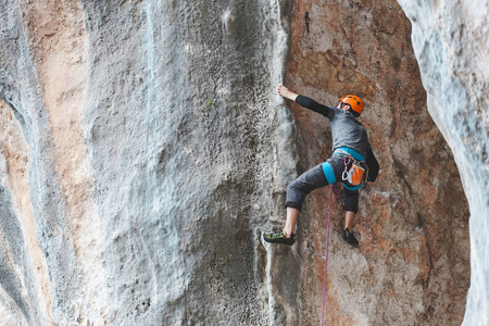 一个戴头盔的人爬上岩石。 在大自然中攀爬。 户外健身。 积极的生活方式。 极限运动。 运动员在自然的解脱中训练。 火鸡攀岩。