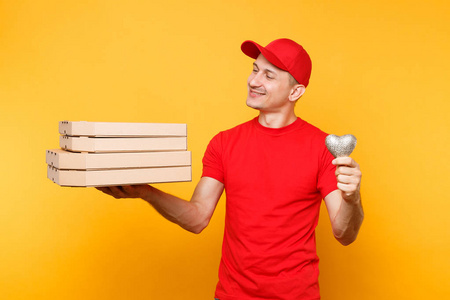 送货员穿着t帽衬衫，在黄色背景上隔离食品订单披萨盒。 男员工皮萨曼快递统一持有心意大利披萨在纸板平板盒。 服务概念