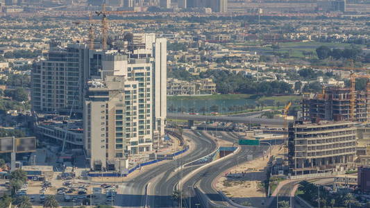 大城市时间推移中道路交叉口的鸟瞰图。 迪拜码头和JLT区的城市景观在阿联酋与汽车和摩天大楼。