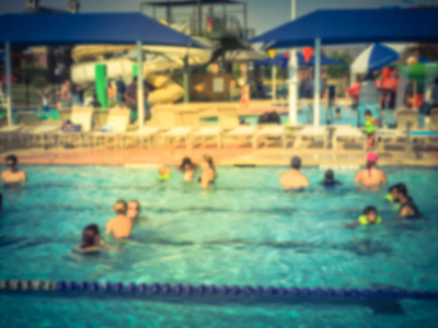 模糊的孩子和他们的父母喜欢在社区室外游泳池游泳和水上活动。 健康的生活方式积极的父母游泳课活动家庭度假水生中心