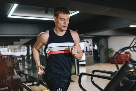 高加索运动员在现代健身房跑步机上做有氧运动的水平镜头。运动，健身，健康生活和人的理念..