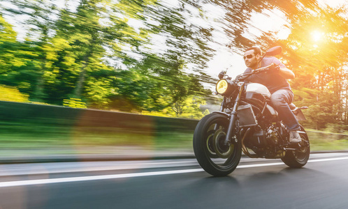 现代扰流器摩托车在森林道路上骑。 在摩托车旅游旅途中驾驶空路玩得很开心。 真正的动态运动模糊镜头。 复制空间为您的个人文本。