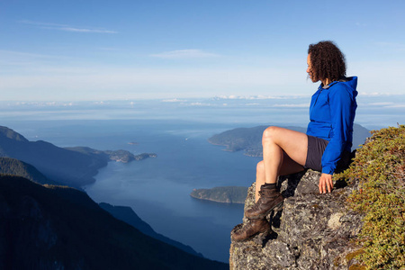 冒险的女人在阳光明媚的夏天在山上欣赏风景。 乘坐不伦瑞克山狮子湾北部温哥华加拿大。