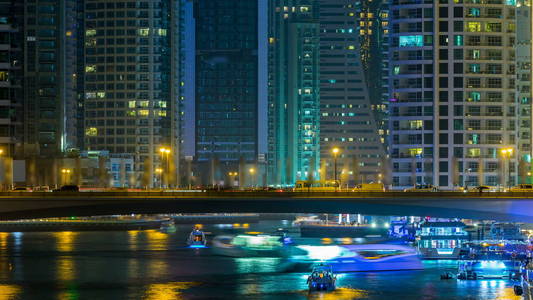 海滨长廊和桥梁与交通在迪拜运河码头时间晚阿联酋。 从桥上看棕榈船和塔楼。 迪拜码头是迪拜的一个地区，有人工运河城市，在波斯容纳超