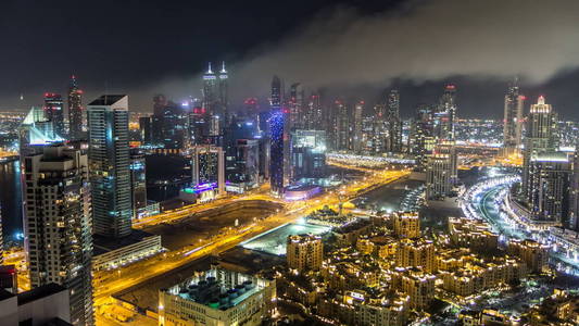 风景优美的鸟瞰一个大的现代城市在夜间时间推移与夜间交通和照明摩天大楼办公楼。 商务湾迪拜阿拉伯联合酋长国。