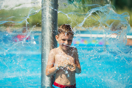 快乐的孩子在海边的一个热带度假胜地游泳池的蓝色水中玩耍。 暑假概念。 可爱的男孩在游泳池里游泳。 在游泳池里嬉戏玩耍