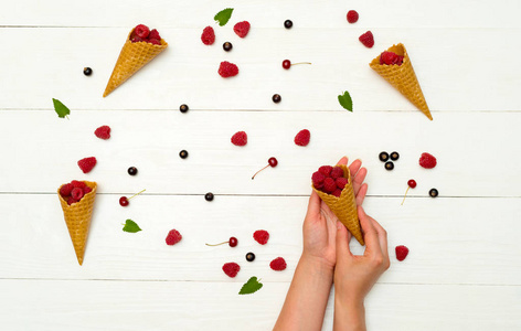 s hands. Fresh berries in cones and on white wooden background. 