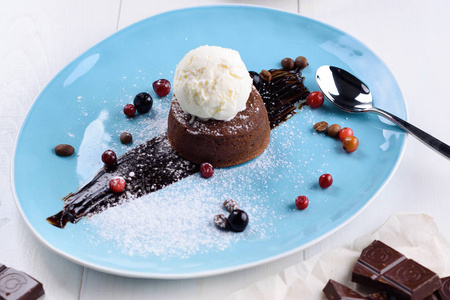 美味的巧克力熔岩蛋糕与香草冰淇淋球和浆果在盘子上的白色桌子关闭。 巧克力火锅。 热巧克力布丁。