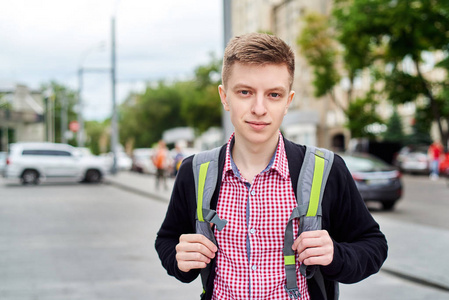 时尚年轻人的肖像穿格子衬衫，背包步行在城市户外自由空间。 旅游和旅游概念