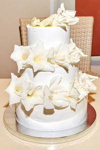 优雅的白色多层次婚礼或生日蛋糕与白色新鲜的菖蒲花装饰在桌子上的自由空间。