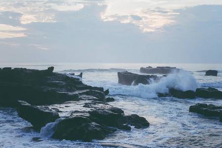 海洋的波浪在岩石上破碎。 日落时溅起海浪。