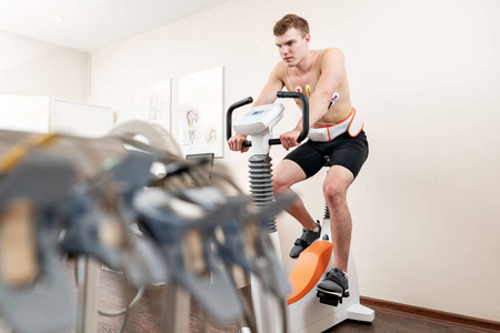 一名男性病人, 脚踏自行车测力计压力测试系统的功能, 他的心脏检查。运动员在医学研究中进行心脏压力测试, 由医生监督