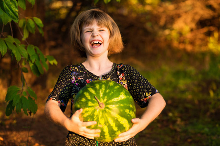 快乐的女孩在晴天抱着很大的西瓜。 健康饮食观念