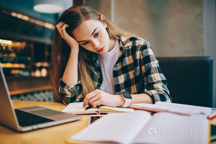 疲惫不堪的女学生在准备重要考试时,试图在室内用现代