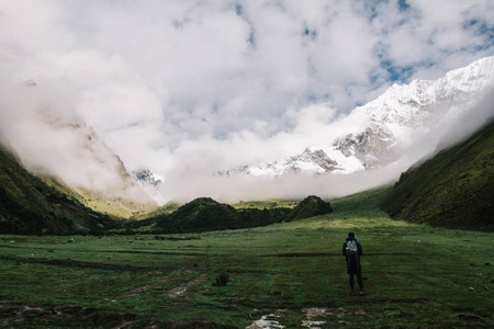 带旅行背包的年轻游客的后景，欣赏南美洲青山的美景。有经验的男性徒步旅行者在秘鲁的托普斯被云层覆盖着自然风景