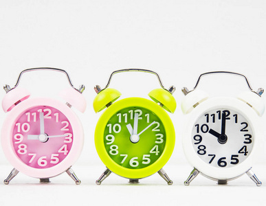 特写彩色闹钟堆叠在罗格林闹钟放在中间的粉红色和白色彩色白色背景。