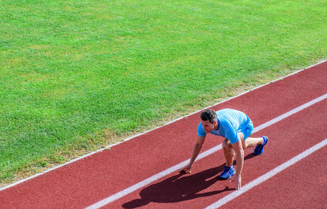 运动员赛跑准备比赛.联合调动练习，提高灵活性和功能..初学者的跑步技巧。男子运动员站低起点位置体育场路径。快跑了。