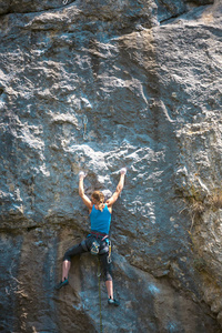 登山者正在训练攀登岩石。 一个强壮的女孩克服了一条艰难的攀爬路线。 积极的生活方式。 极端的爱好。 一个女人在大自然中参加运动。