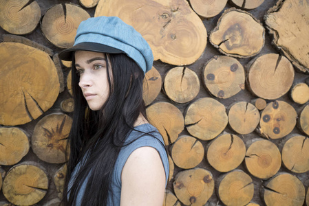 木制背景上的女孩肖像。戴着蓝色帽子的女孩。戴帽子的女孩的肖像。美丽的黑发