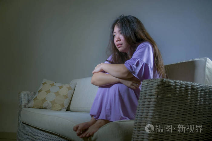年轻的悲伤和沮丧的亚洲韩国妇女在家沙发沙发上哭泣,绝望和无助,痛苦