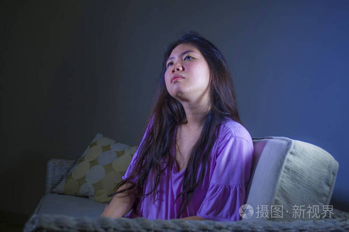年轻的悲伤和沮丧的亚洲妇女在家沙发沙发上哭泣,绝望
