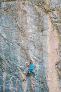 登山者正在训练攀登岩石。 一个强壮的女孩克服了一条艰难的攀爬路线。 积极的生活方式。 极端的爱好。 一个女人在大自然中参加运动。