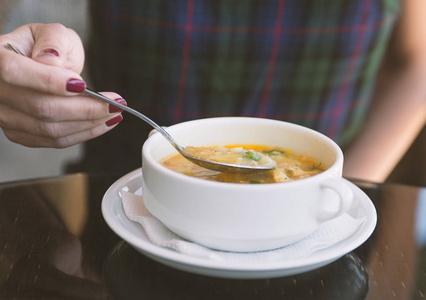 s hand with the spoon while eating soup in the restaurant