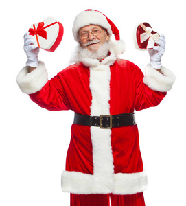 圣诞节。微笑的圣诞老人在白色手套持有两个红色和白色的心形礼品盒与丝带。慷慨的礼物的概念。在白色背景上被隔离