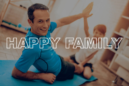 父子正在做健身房。 体育家庭。 健康的生活方式。 活跃的假期。 锻炼衣服。 变得更好。 在家里锻炼。 健身房地毯。 重复练习。 