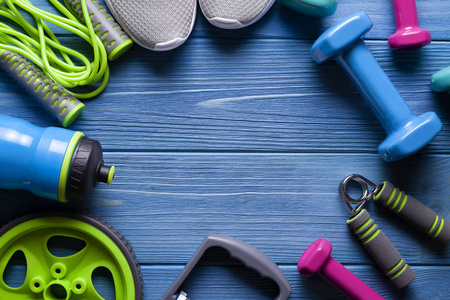  jumping rope, water bottle and dumbbell on blue wooden board