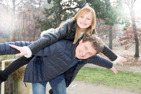 父亲和女儿在秋季冬季公园的家庭观念中玩得很开心