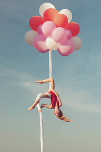 女孩在空中的画布上玩把戏。 气球把帆布放在空中。
