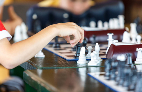 可爱的聪明英俊的男孩穿着白色T恤下棋。 教育理念智力游戏。 国际象棋课程的概念