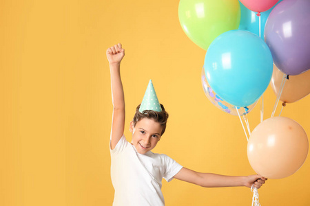 可爱的小男孩戴着生日帽，带着彩色背景的气球