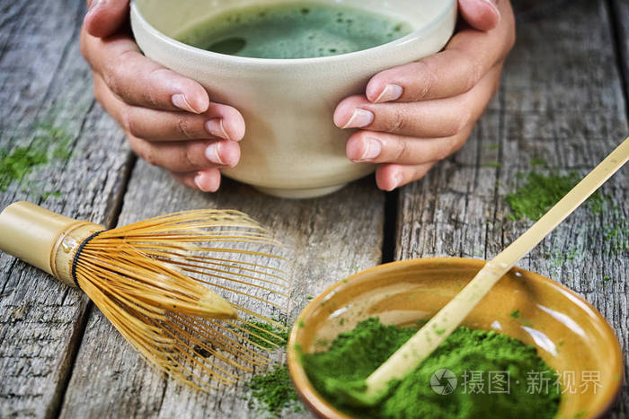 女孩手捧旳茶在特殊的旳茶碗里用竹勺和扫