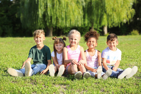 可爱的小孩子坐在户外绿草地上
