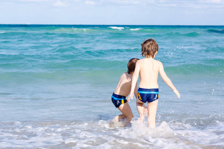 两人开心的小孩子男孩在海洋沙滩上运行。有趣可爱的儿童 兄弟姐妹 双胞胎和最好的朋友制作的假期，享受夏天暴风雨阳光灿烂的夏天一