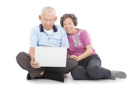 快乐的老年夫妇用笔记本电脑看或靠