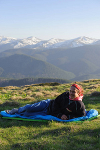 快乐的旅行者躺在地上，从山顶欣赏风景